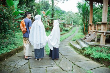 Çocuğu olan Müslüman bir aile birlikte yürüyor ve el ele tutuşuyorlar.
