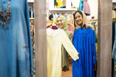 Heyecanlı Asyalı Müslüman kadın yeni kıyafetler deniyor.