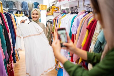 Başörtülü müslüman kadınlar yeni elbisenin fotoğrafını çekiyorlar.