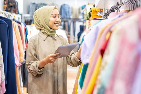 Завуальована жінка тримає планшет під час роботи в магазині моди — стокове фото