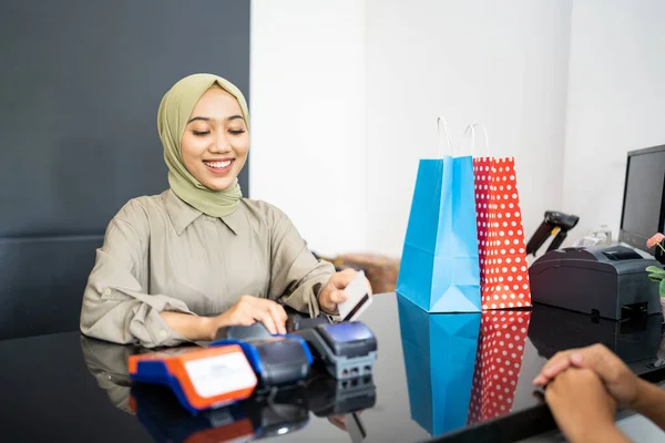 Frau lächelt, als sie der Kassiererin beim Bezahlen Kreditkarten gibt — Stockfoto