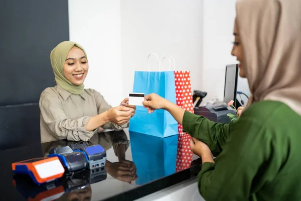 Mujer sonríe mientras le da tarjetas de crédito al cajero mientras paga —  Fotos de Stock