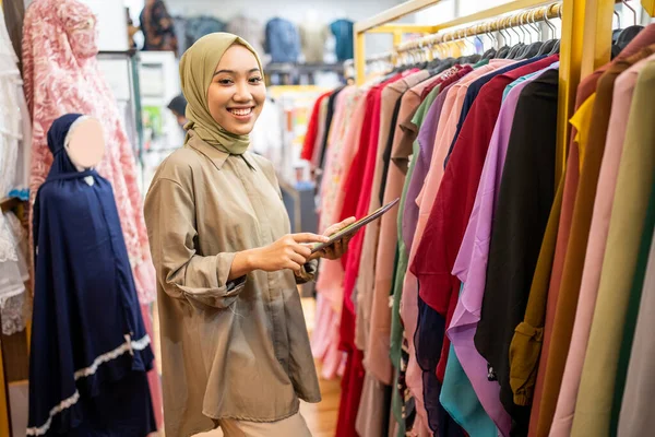 Moda mağazasında çalışırken peçeli kadın tableti tut