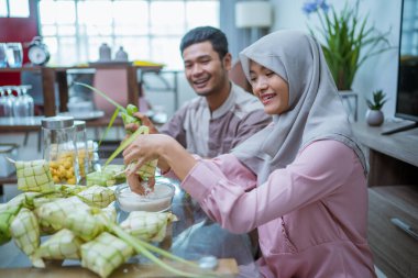 Müslüman çift Idul Fitri geleneksel lezzeti için ketupat yapıyor.