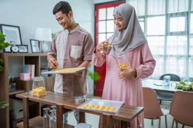 Müslüman adam ve kadın, Idul Fitri için nastar yemeği pişiriyor.