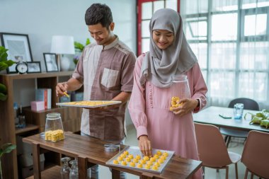 Müslüman adam ve kadın, Idul Fitri için nastar yemeği pişiriyor.