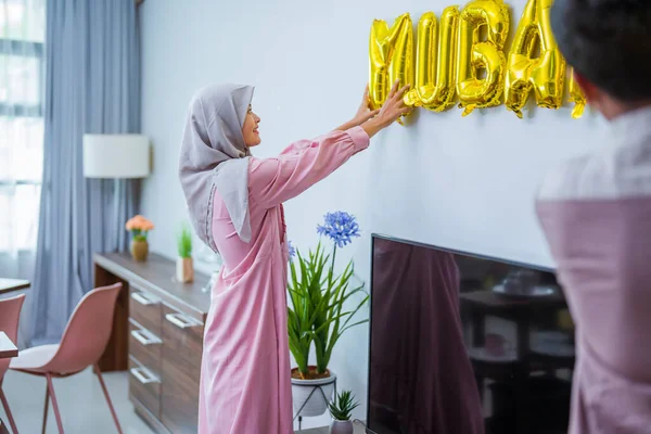 Pasangan muslim menghiasi rumah mereka dengan teks eid mubarak di dinding — Stok Foto