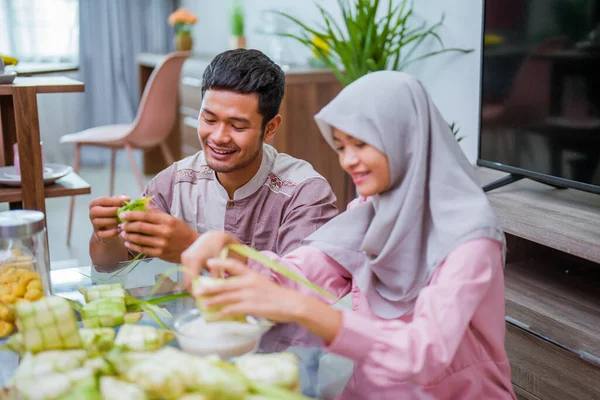 Muslimský pár asijský výroba ketupat rýže koláč doma pomocí palmového listu — Stock fotografie