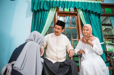 Müslüman kız diz çöküp anne ve babasının elini sıkar ve af diler.