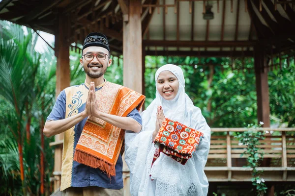 Par med muslimska kläder tittar på kameran visar hälsning — Stockfoto