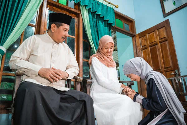 Müslüman kız diz çöküp anne ve babasının elini sıkar ve af diler.