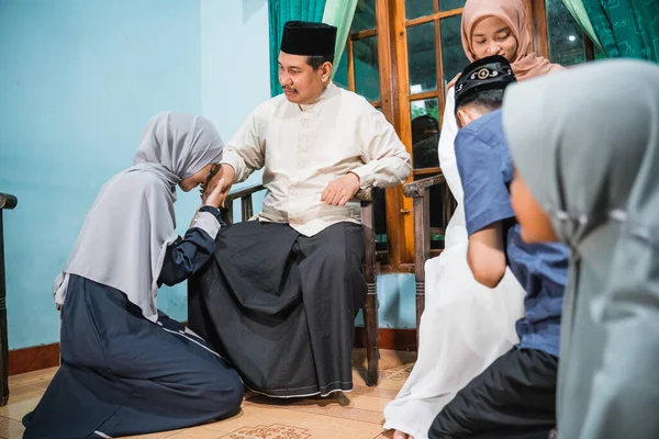 Мусульманская дочь преклоняет колени и пожимает родителям руку, прося прощения. — стоковое фото