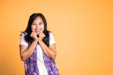 Asyalı bir kadın kameraya bakıp eğlenceli bir hareketle gülümsüyor.