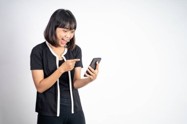 Heyecanlı Asyalı kadın cep telefonunu işaret ederek gülüyor