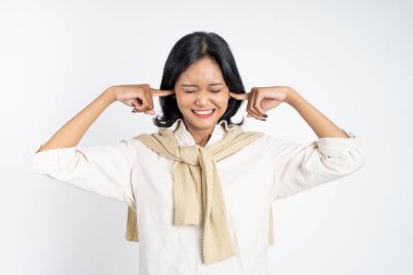 İki eliyle kulaklarını kapatan sinirli yüzlü bir kadın.