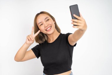 V işaretli cep telefonu kamerası kullanan genç bir kadın selfie 'si