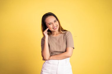 Asyalı bir kadın kameraya bakıp eğlenceli bir hareketle gülümsüyor.