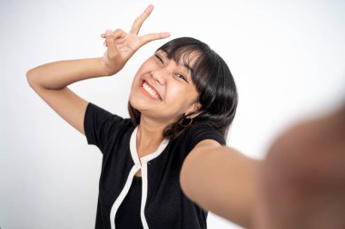 V işaretli cep telefonu kamerası kullanan genç bir kadın selfie 'si