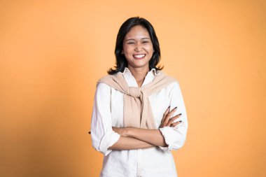 Asyalı kadın kameraya bakıyor çapraz kolla gülümsüyor.