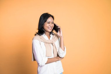 Kadın izole edilmiş bir arka planda cep telefonuyla arama yapıyor.