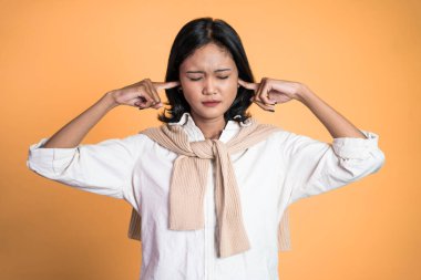 İki eliyle kulaklarını kapatan sinirli yüzlü bir kadın.