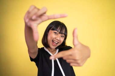 Kadın parmaklarının arasından kameraya bakıyor ve bir çerçeve oluşturuyor