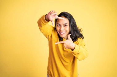 Kadın parmaklarının arasından kameraya bakıyor ve bir çerçeve oluşturuyor