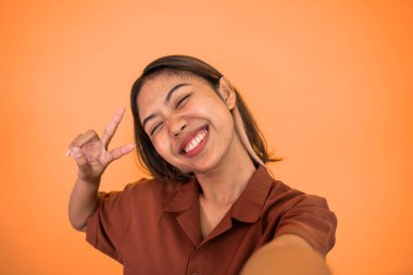 V işaretli cep telefonu kamerası kullanan genç bir kadın selfie 'si