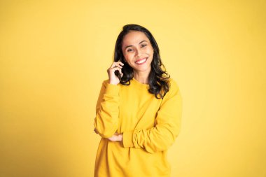 Kadın izole edilmiş bir arka planda cep telefonuyla arama yapıyor.