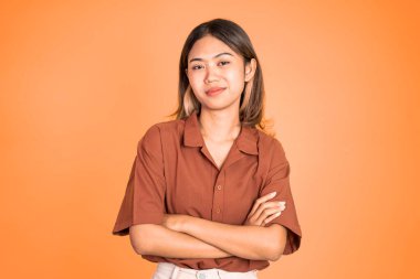 Asyalı kadın kameraya bakıyor çapraz kolla gülümsüyor.