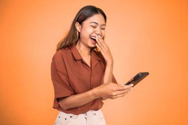 Heyecanlı Asyalı kadın cep telefonunu işaret ederek gülüyor