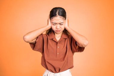 İki eliyle kulaklarını kapatan sinirli yüzlü bir kadın.