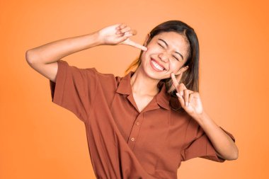 Mutlu Asyalı kadın yanaklarını tutarken gülüyor..