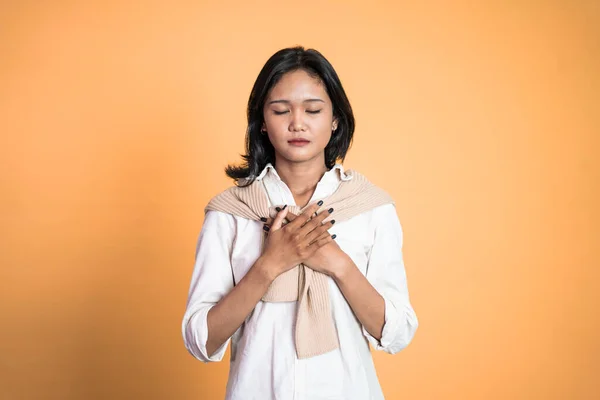 Asiática joven sosteniendo pecho mientras se siente aliviado —  Fotos de Stock