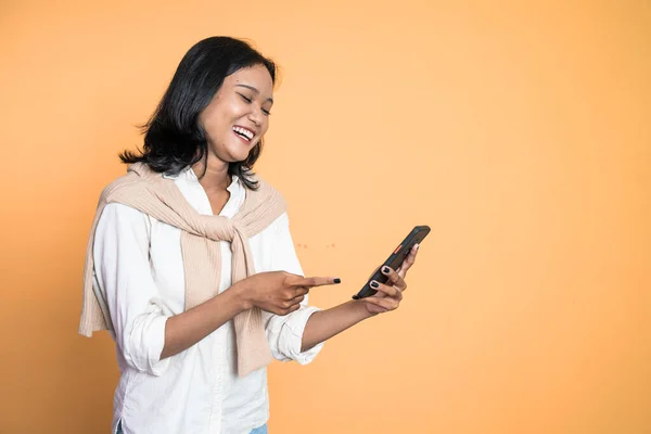 Excited asian woman laugh with finger pointing on her mobile phone — Stock fotografie