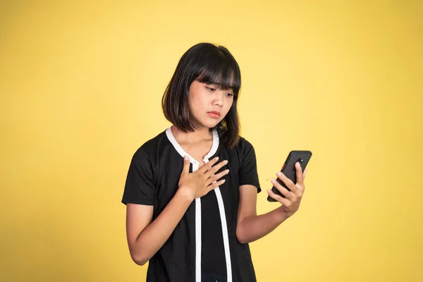 Droevige aziatische jonge vrouw tijdens het gebruik van mobiele telefoon — Stockfoto