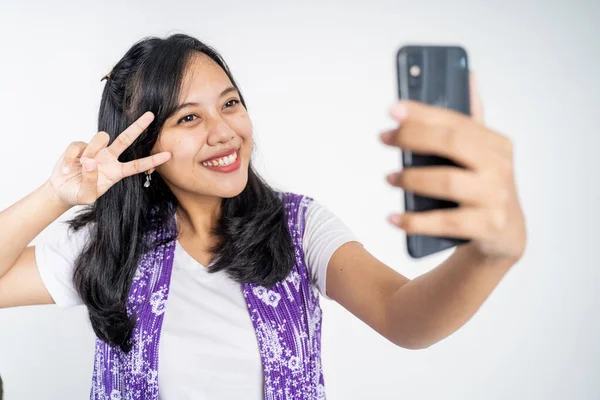 Селфи молодой женщины с помощью камеры мобильного телефона с V знак — стоковое фото