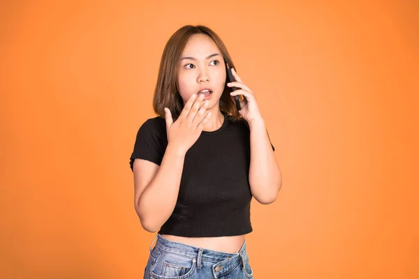 Chockad asiatisk kvinna ringer ett samtal med hjälp av en mobiltelefon — Stockfoto