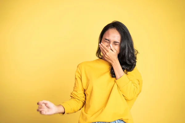 Жінка сміється жорстко прикриває рот на жовтому фоні — стокове фото