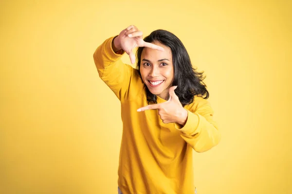 Woman looking at the camera from between fingers forming a frame — Stockfoto