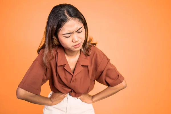 Giovane donna asiatica nel dolore con entrambe le mani tenendo lo stomaco — Foto Stock