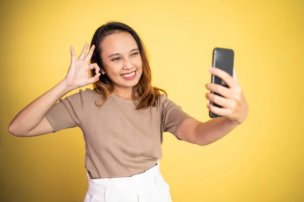 Kvinna ta en selfie med ok händer gest på isolerade — Stockfoto