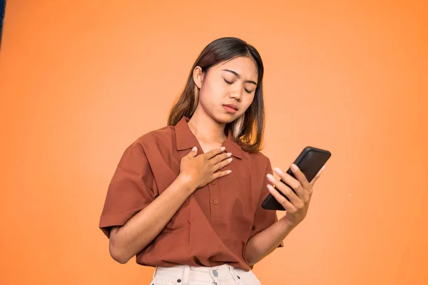 Sad asian young woman while using mobile phone — ストック写真