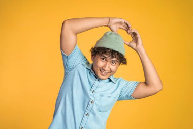 İzole edilmiş arka planda parmak hareketleriyle kalp oluşturan bir adam.