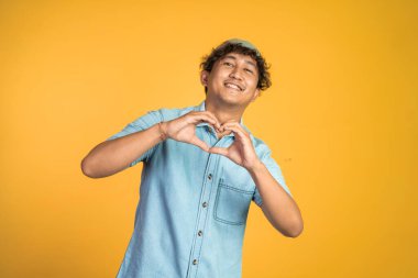 İzole edilmiş arka planda parmak hareketleriyle kalp oluşturan bir adam.