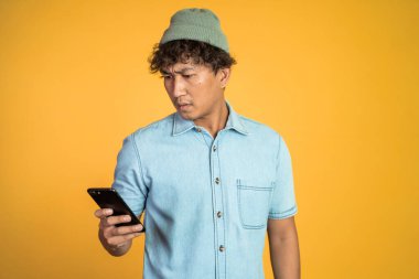 Asyalı genç adam cep telefonunun ekranına bakıyor.