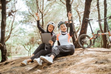 İki peçeli kız tablet ve kulaklık kullanarak şarkı dinliyorlar.