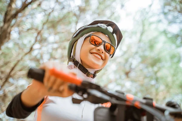 Spodní pohled na atraktivní zahalená dívka v slunečních brýlích na kole — Stock fotografie