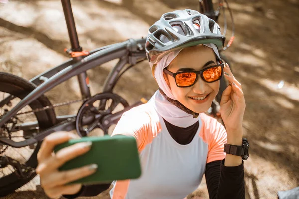 Güneş gözlüklü kız akıllı telefon fotoğrafında selfie için poz veriyor.