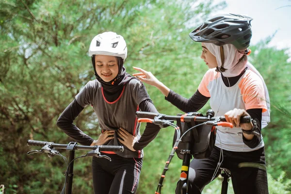 Bir kadının arkadaşlarıyla bisiklete binerken midesi ağrır.